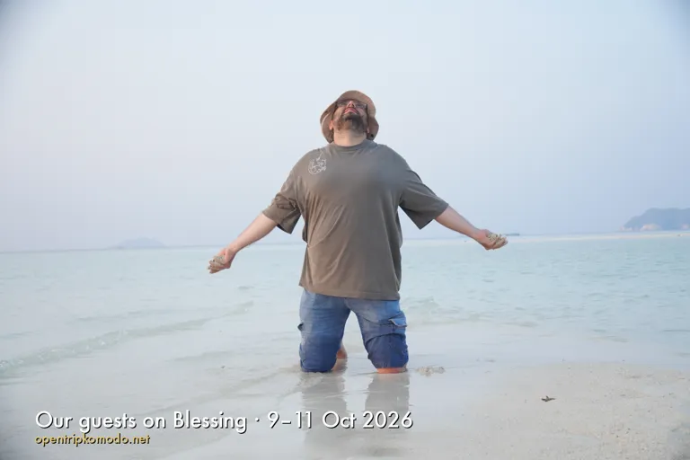 Tamu trip Blessing berlutut di air dangkal sambil merentangkan tangan