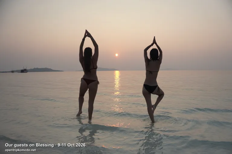 Dua tamu trip Blessing berpose yoga di air saat matahari terbenam