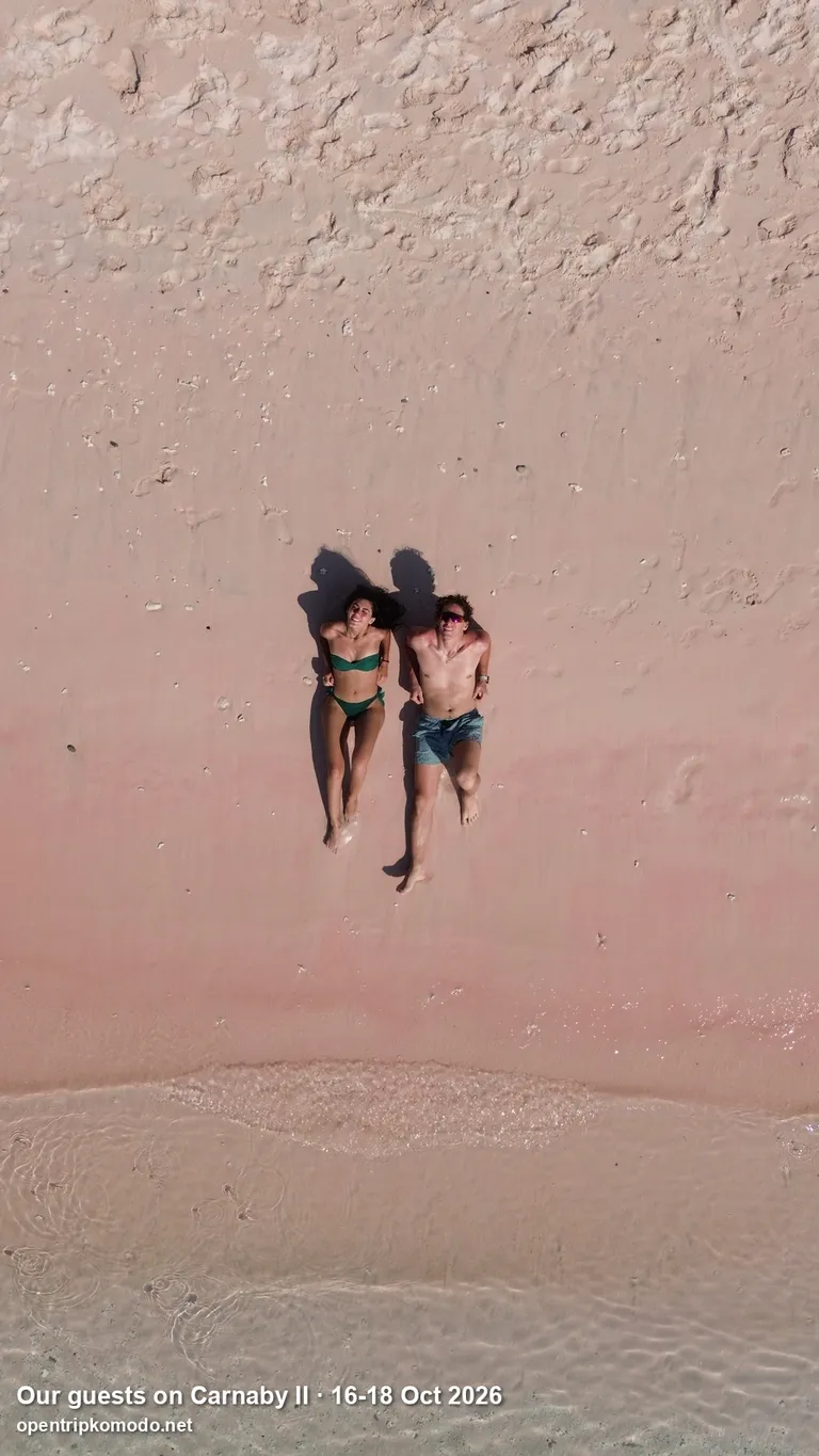 Dua tamu trip Carnaby II berbaring di pasir merah muda Pink Beach, dari atas