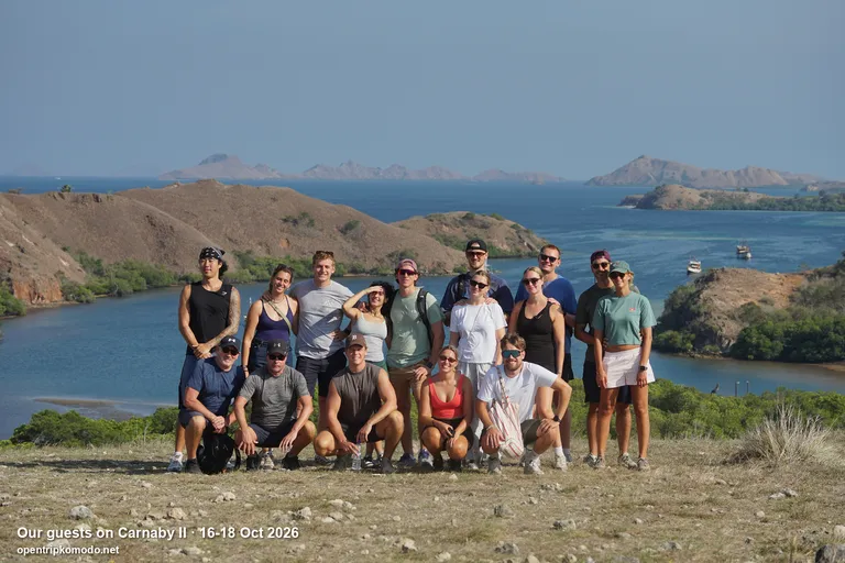 Rombongan tamu trip Carnaby II berfoto di bukit dengan teluk dan pulau di belakang