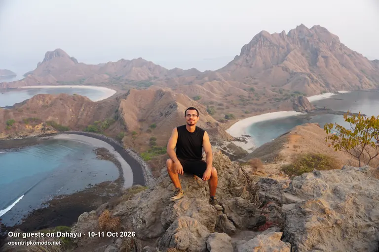 Tamu trip Dahayu duduk di puncak Pulau Padar dengan tiga teluk di belakangnya