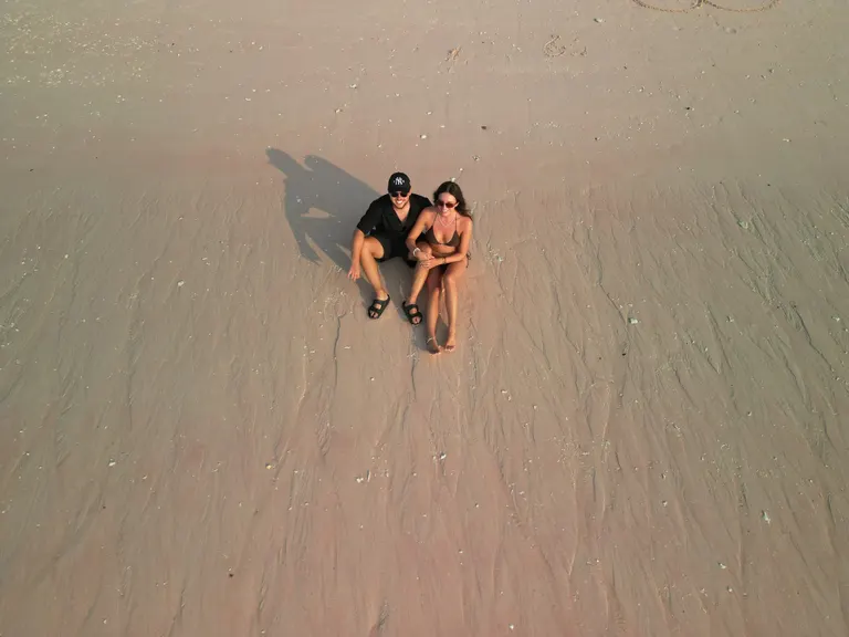 Dua tamu trip Deden Putra berbaring di pasir merah muda Pink Beach, dari atas