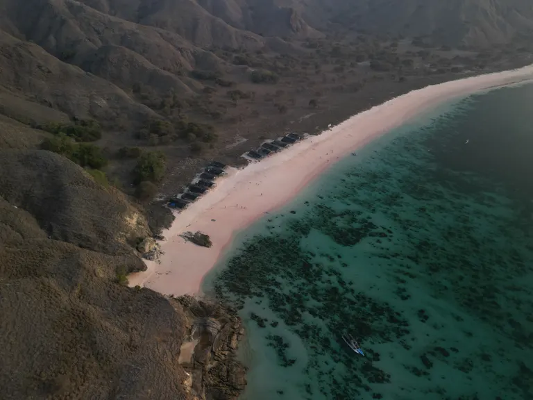Pink Beach dari udara, pasir merah muda di antara bukit dan air jernih