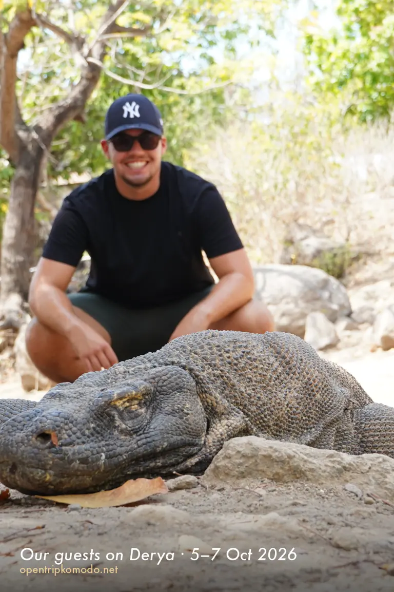 Tamu trip Derya berjongkok di belakang komodo di Pulau Komodo