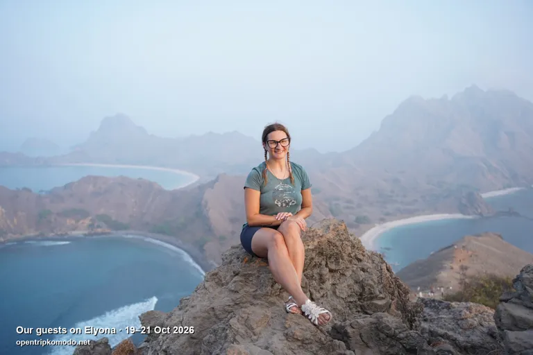 Tamu Elyona duduk di bukit Padar dengan pemandangan tiga teluk