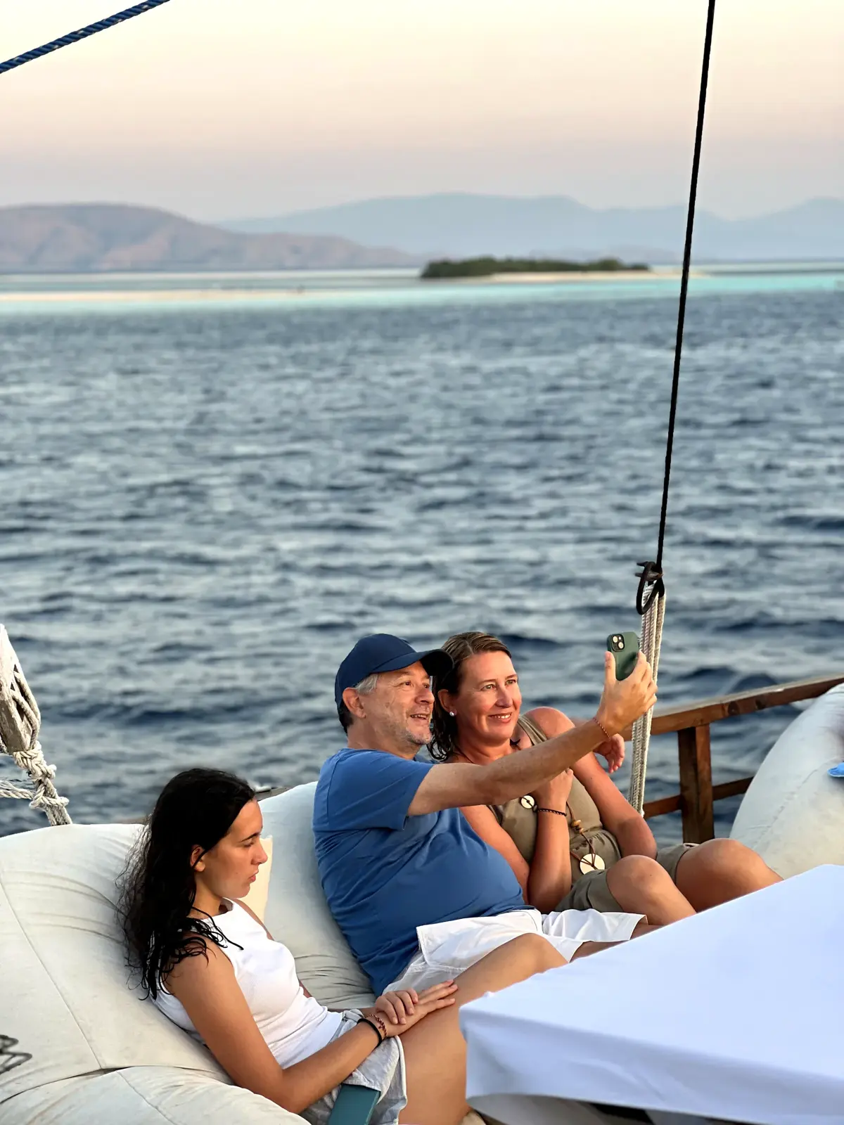 Guests toasting on deck facing the sea at sunset