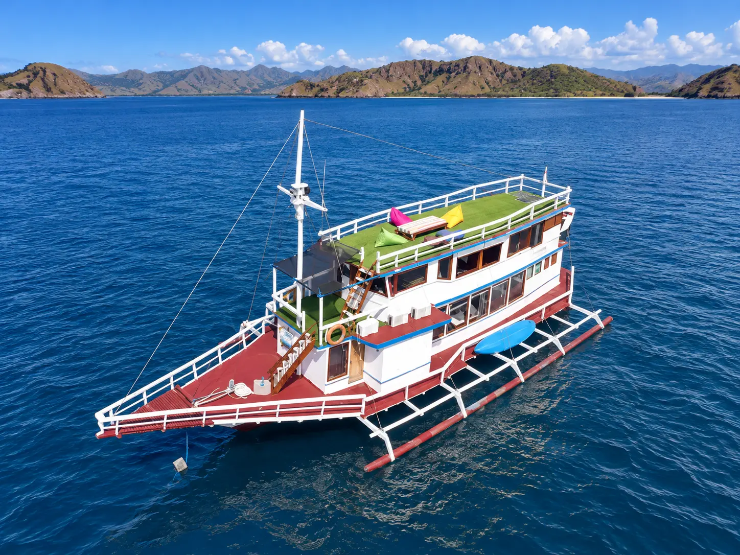 3 Island, a multi-deck boat with a red hull and outriggers in Komodo National Park waters