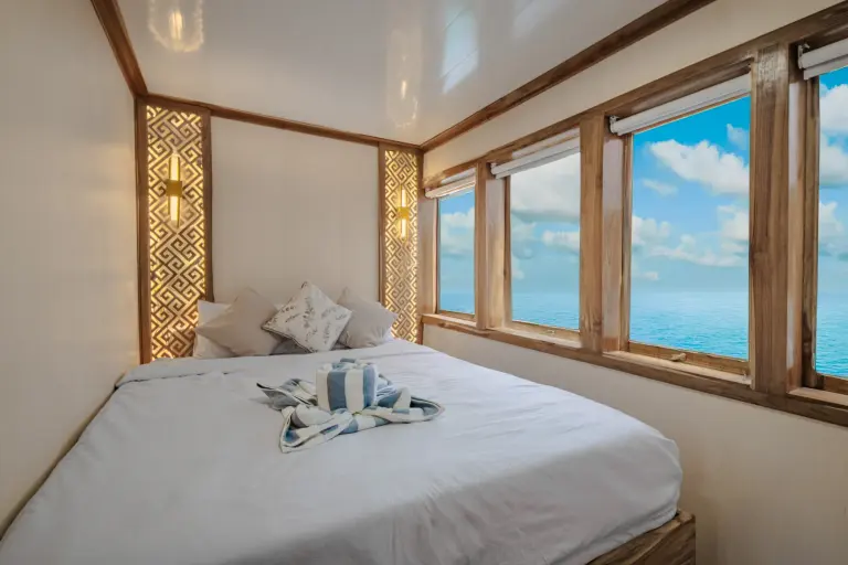 Deluxe Cabin Ahsana dengan queen bed dan deretan jendela laut