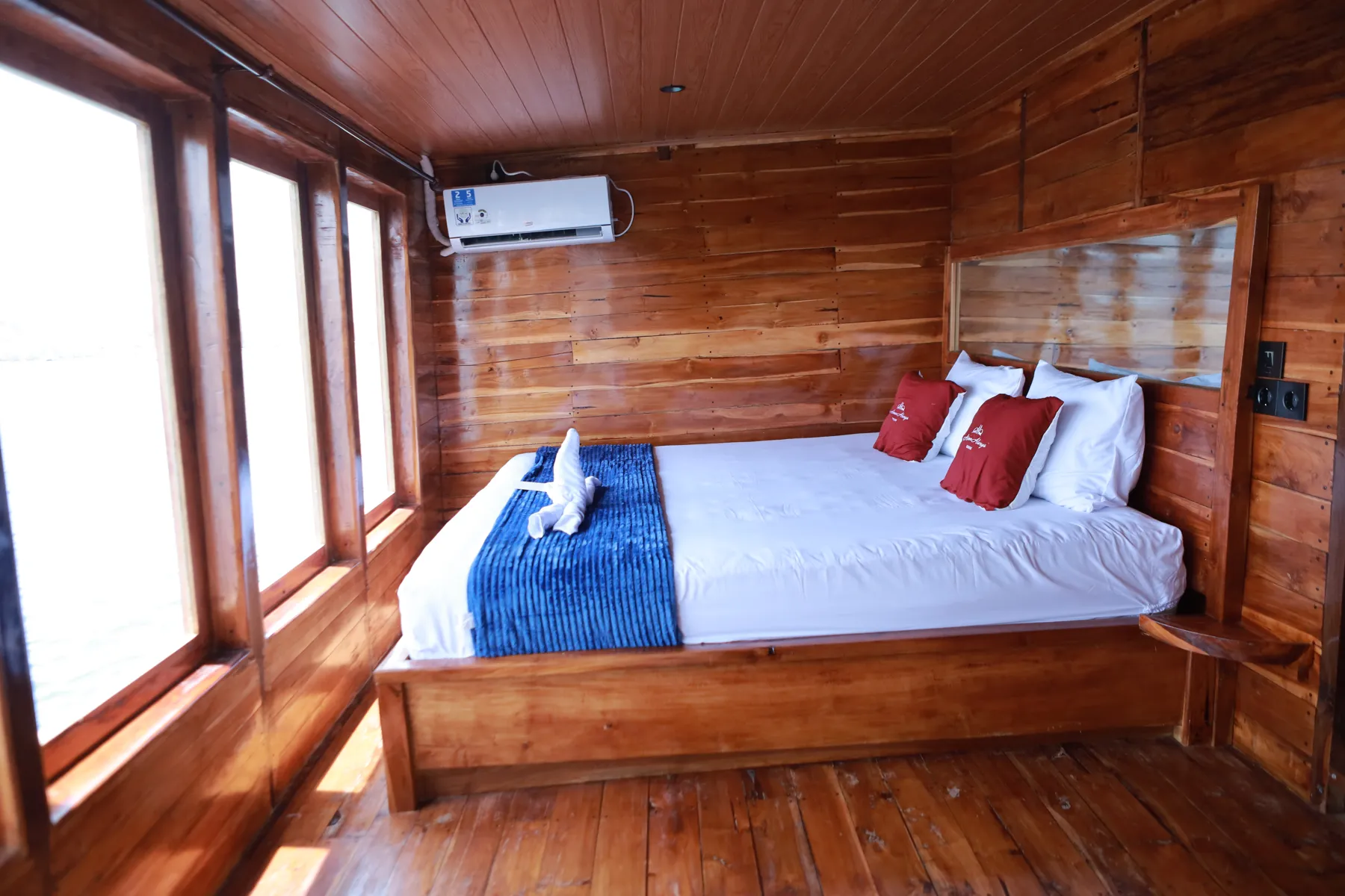 Aimar Deluxe Cabin Tambora, a double bed in a teak-walled cabin