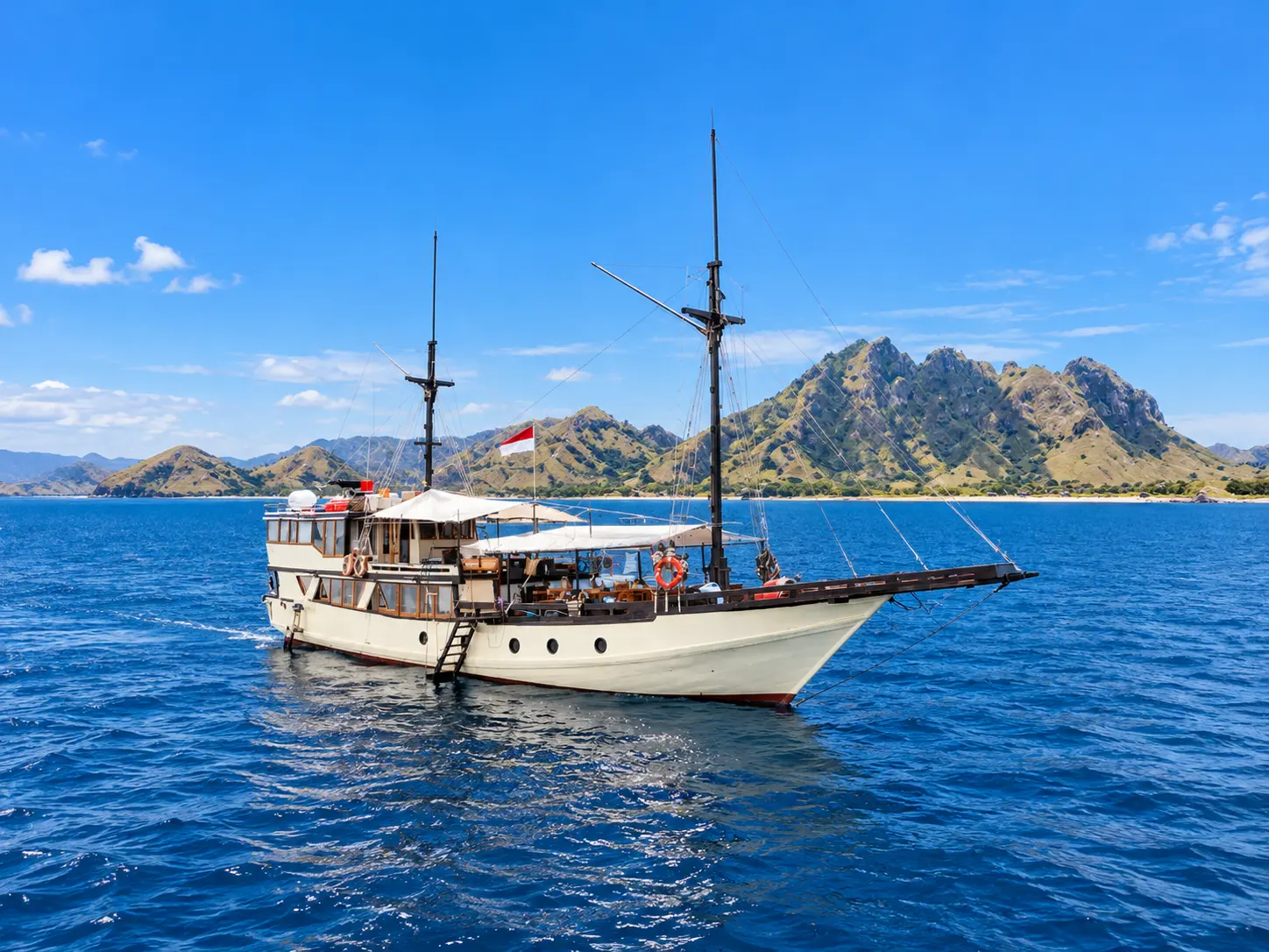 Alfathran, a cream-hulled phinisi with two masts in Komodo National Park waters