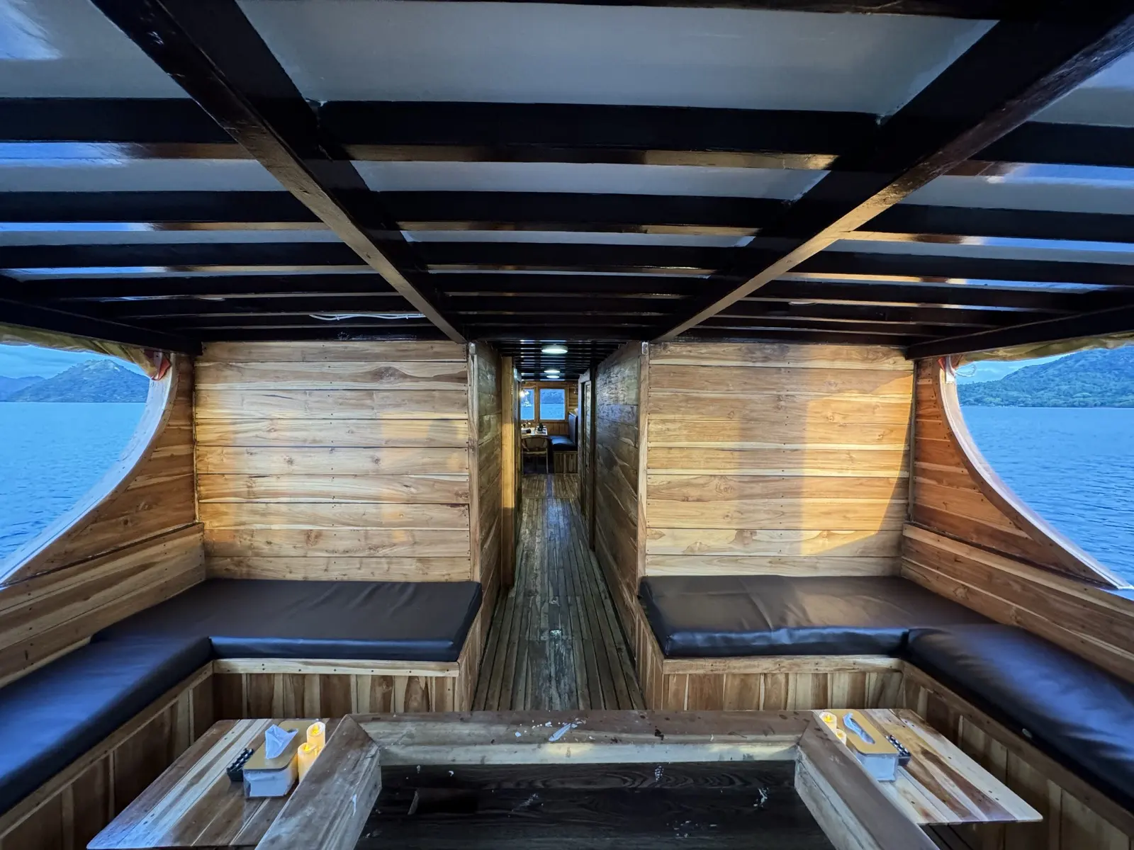 Lounge berbumbung Bajo Sunset Voyages dengan sofa bangku panjang dan tingkap terbuka di kedua-dua sisi