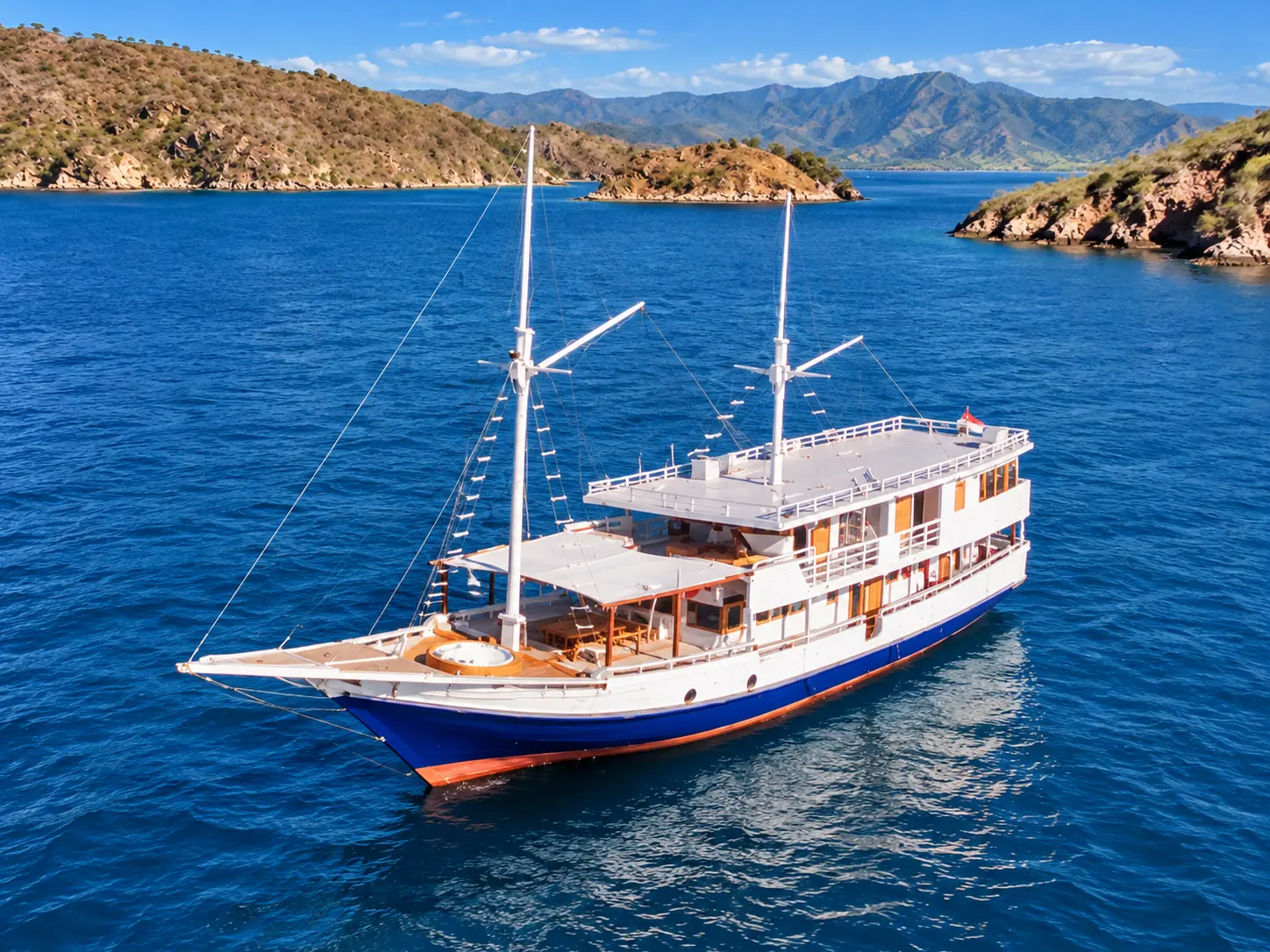 Bombana 02, a phinisi with a white and blue hull in Komodo National Park waters