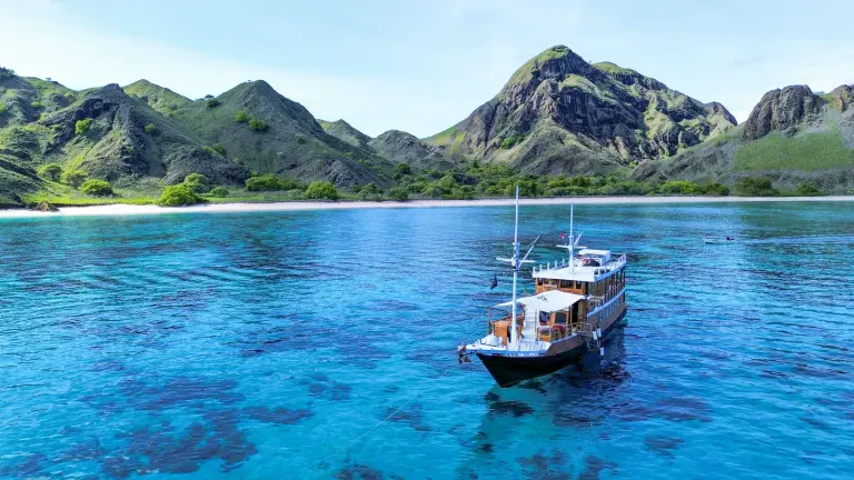 Kapal kayu Capt Octopus berlabuh di perairan biru depan Pulau Padar