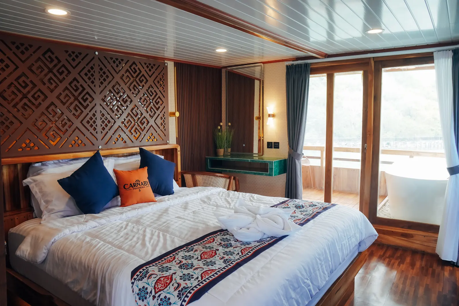 Master Cabin dek atas Carnaby II, ranjang double berkepala ukiran dan pintu kaca ke balkon