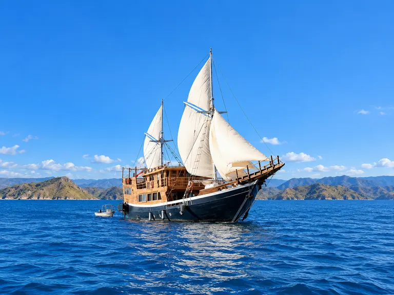Cordelia, phinisi kayu dengan layar putih terkembang di perairan Taman Nasional Komodo