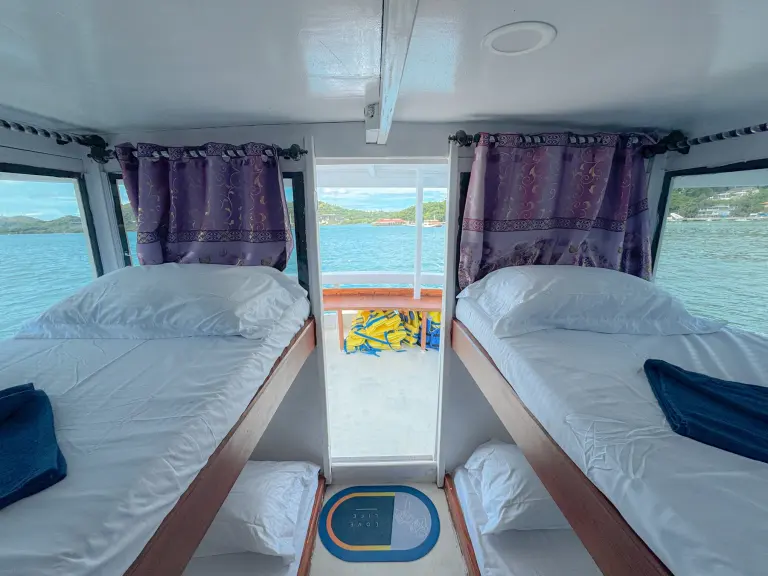 Share Cabin Upper Deck Deden Putra dengan ranjang tingkat single dan jendela ke laut