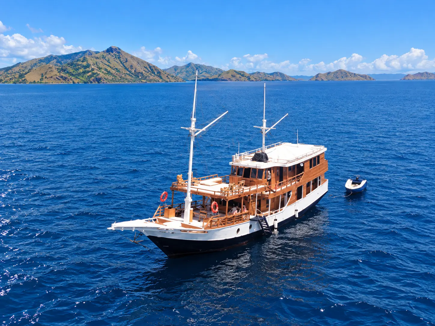 El Ashar, a white-hulled wooden phinisi with two masts in Komodo National Park waters