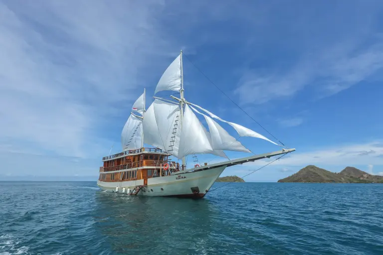 Phinisi Elrora berlayar dengan layar terkembang di perairan Labuan Bajo