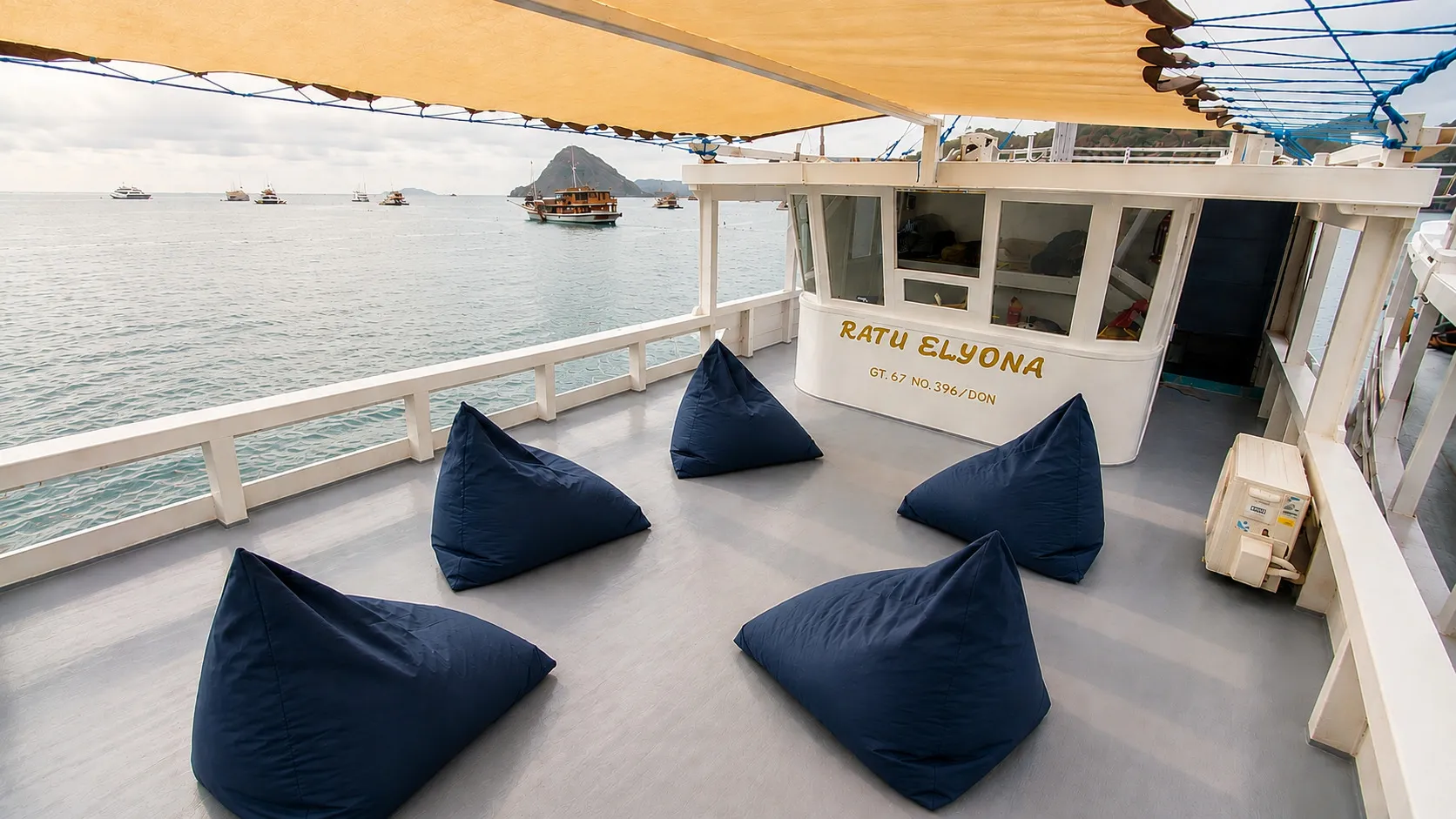 Area santai Elyona dengan bean bag biru di bawah kanopi menghadap teluk