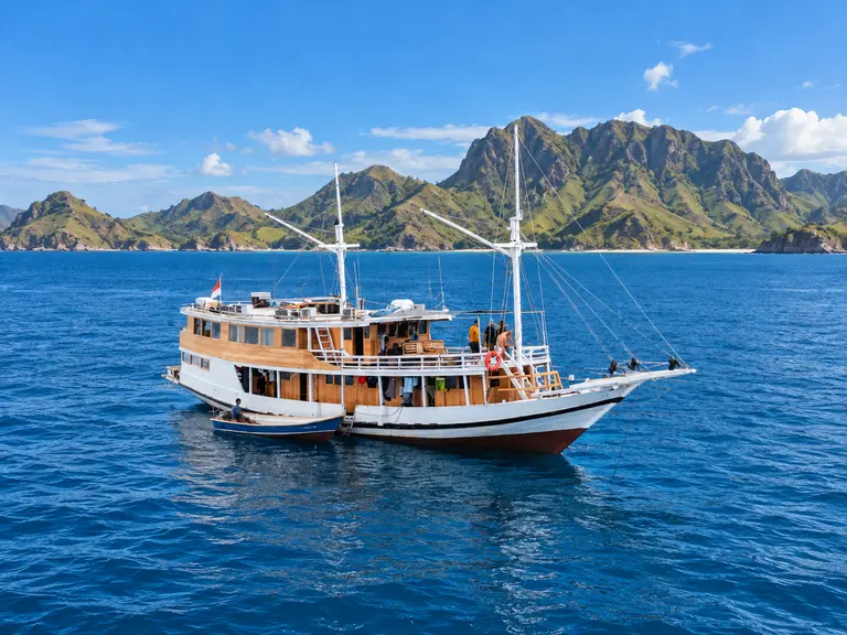 Flores Utama, a white-hulled wooden phinisi with two masts in Komodo National Park waters