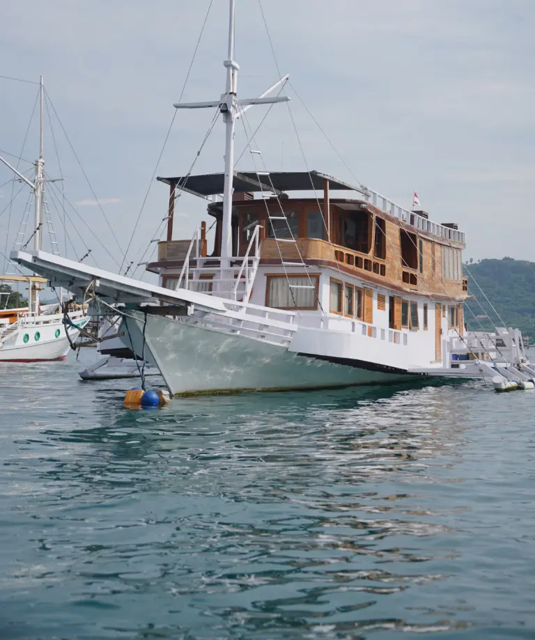 Phinisi Fortuna berlambung putih dengan bangunan kayu berlabuh di pelabuhan Labuan Bajo