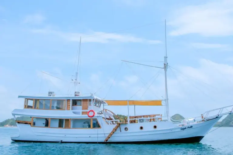 The white phinisi Gajah Putih sailing in Komodo waters under a clear sky