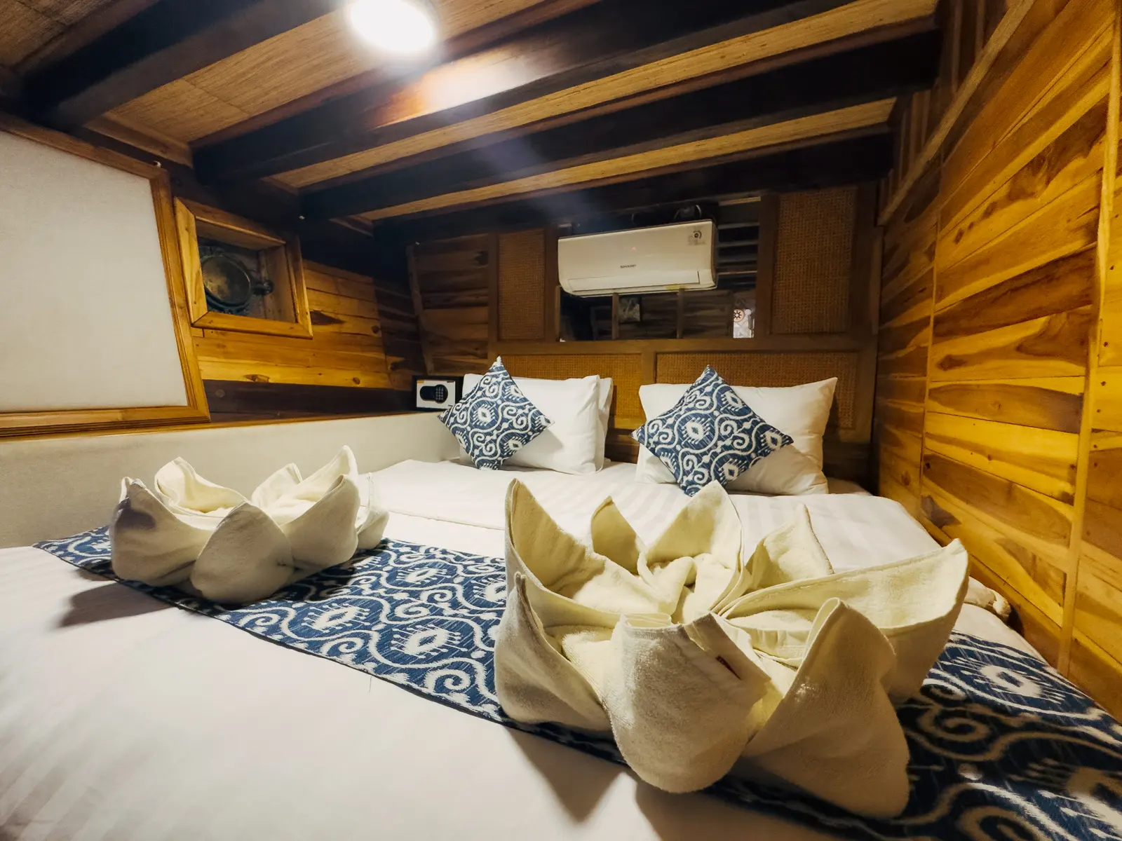 Deluxe Cabin Gammara di dek bawah dengan dinding kayu dan bantal bercorak biru