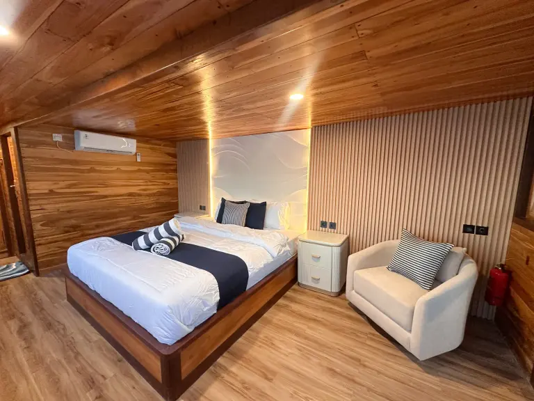 Kabin Atlantic Vhalé dengan ranjang queen, sofa putih, dan dinding kayu bergaris