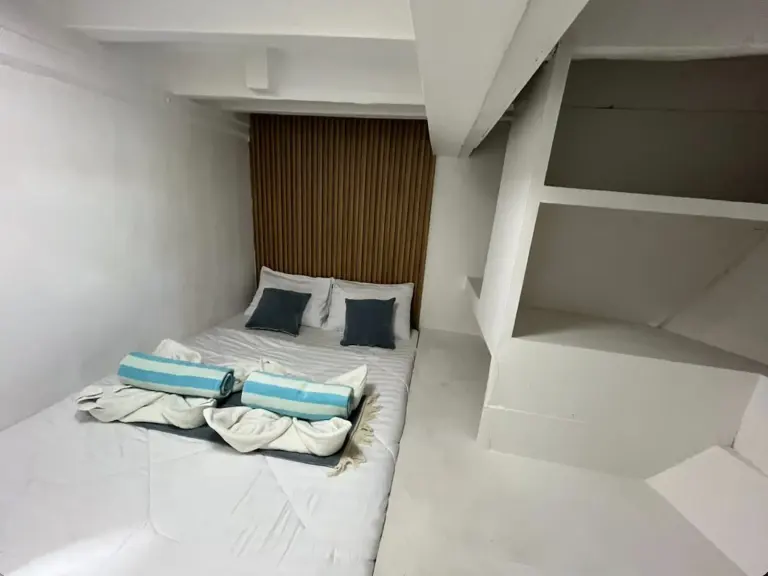 Kabin Burangrang dengan dua kasur single dan rak dinding putih