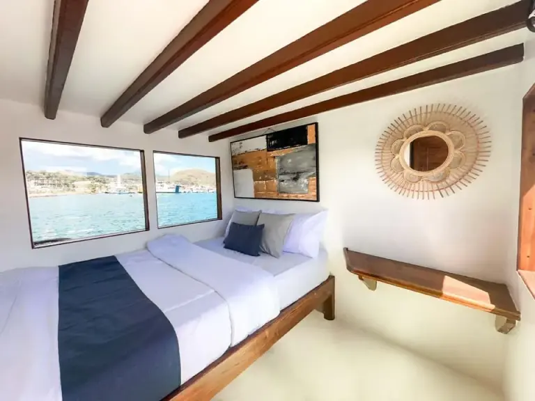 Master Cabin North Blue dengan ranjang double dan dua jendela laut