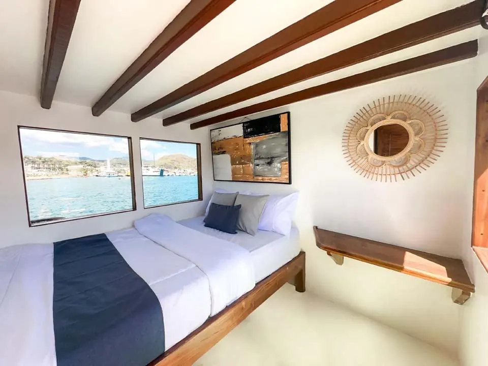 Master Room North Blue dengan ranjang double dan dua jendela laut