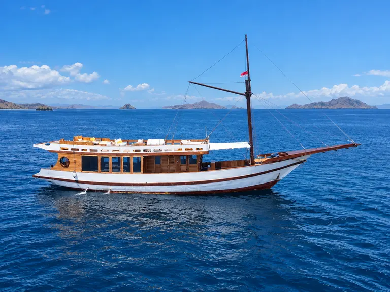 Kala Senja, a slender white-hulled wooden phinisi in Komodo National Park waters