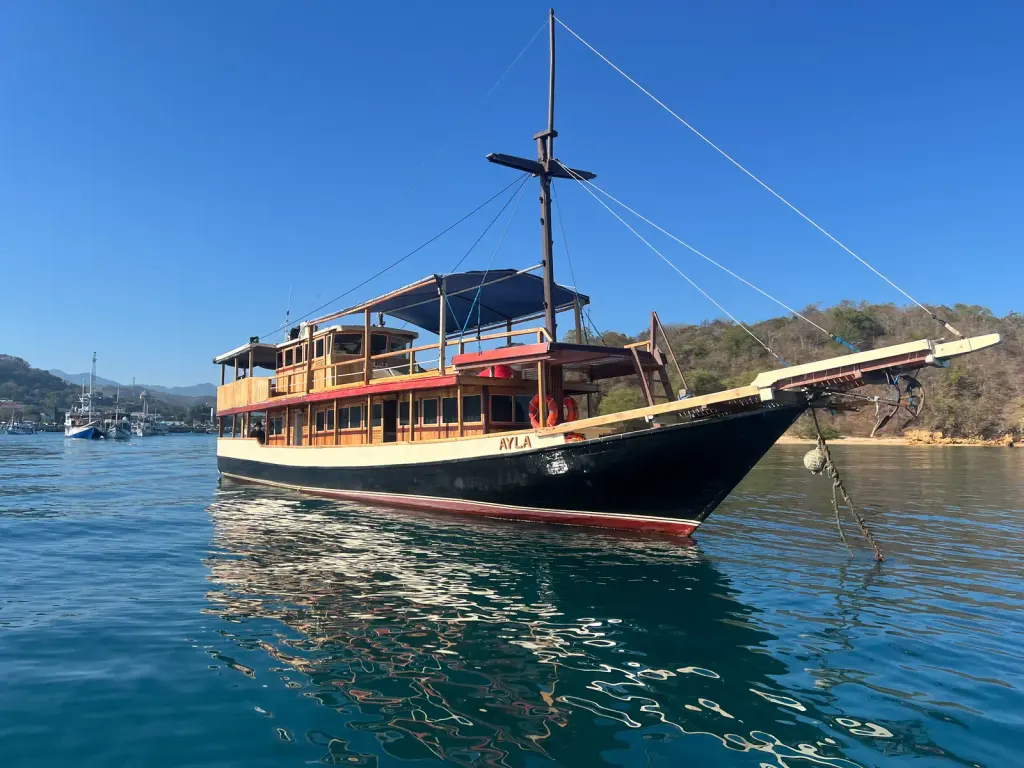 Kapal Ayla berlabuh di perairan Labuan Bajo dengan bukit di belakangnya