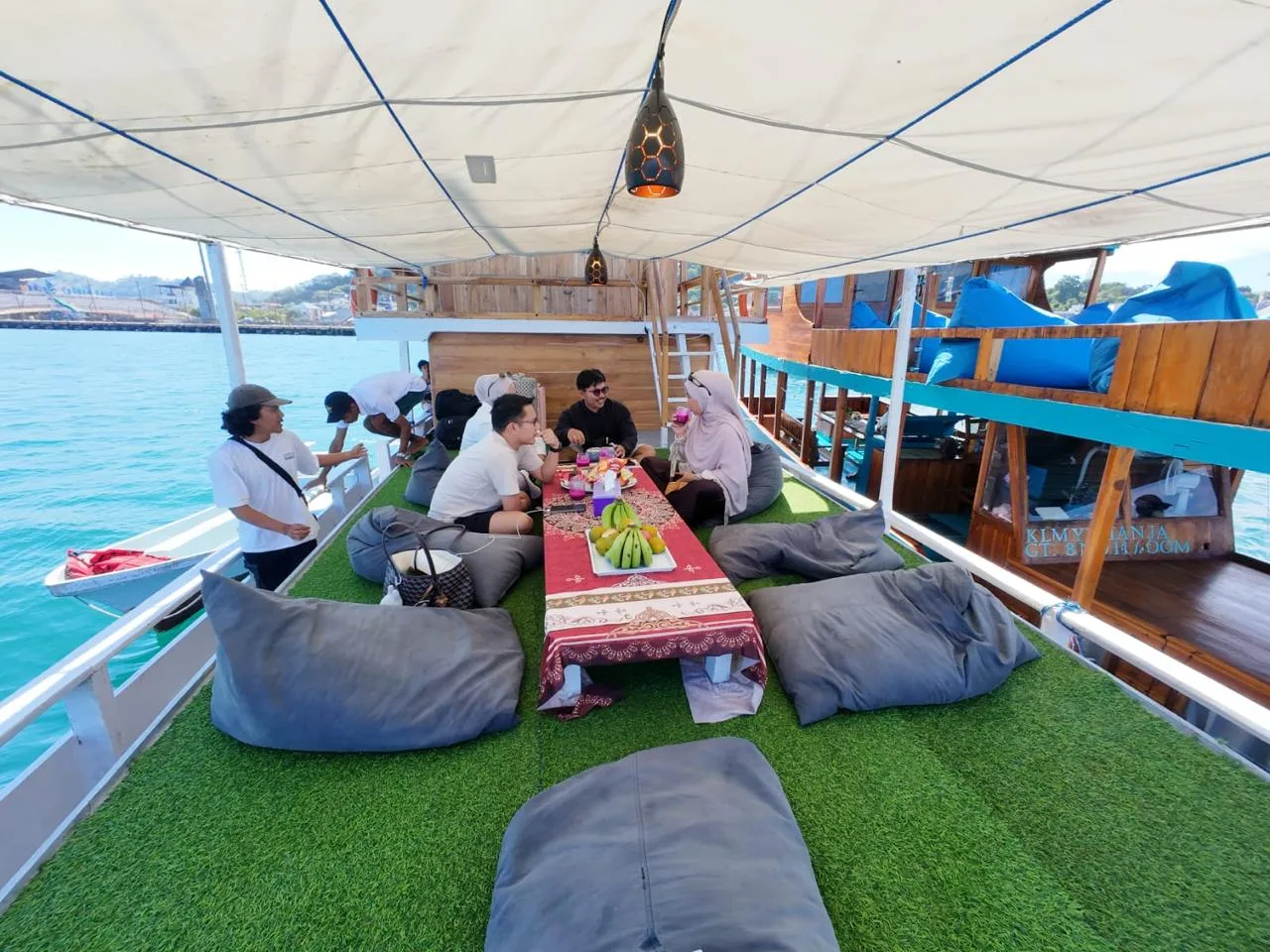 Guests relaxing on the KLM Arimbi upper deck with artificial grass, beanbags and a low table