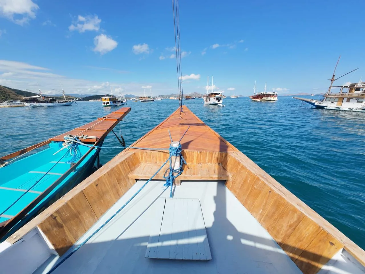 The wooden bow of KLM Arimbi facing Labuan Bajo bay full of boats