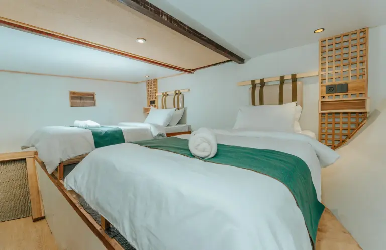 Sharing Cabin 2 Marea, dua ranjang berselempang hijau dan lampu baca di dinding