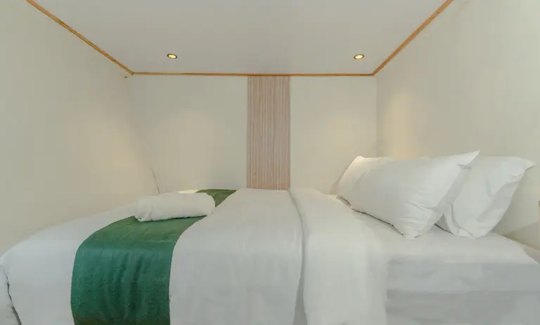 Superior Cabin Marea, ranjang lebar berbantal putih dan selempang hijau
