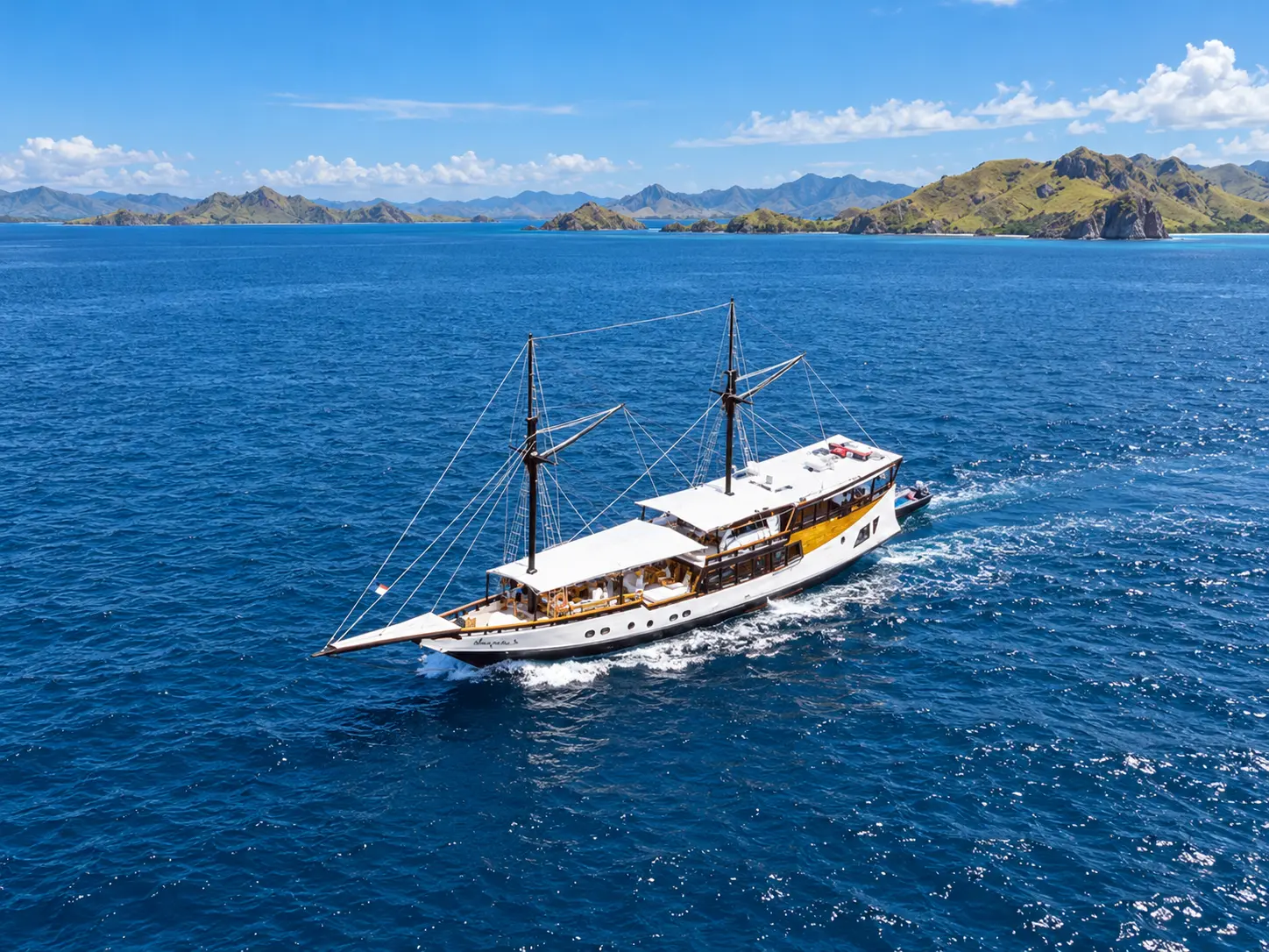 Navila, a white two-masted phinisi under way on blue water in Komodo National Park waters