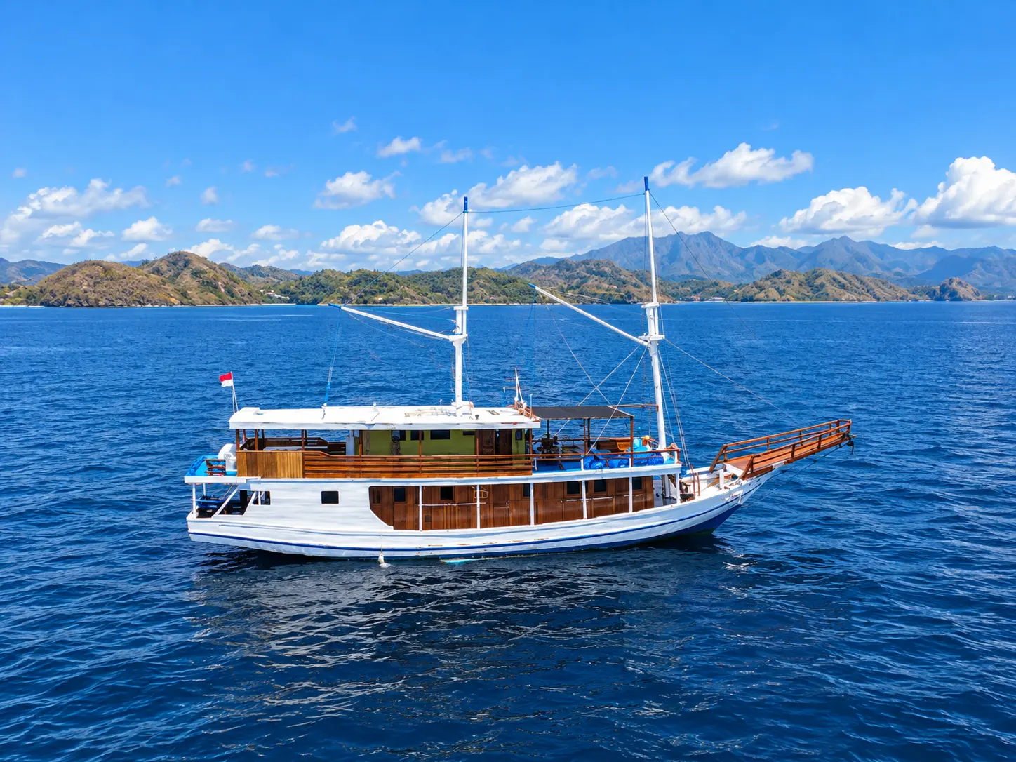 Nemmo, a white-hulled wooden phinisi with two masts in Komodo National Park waters