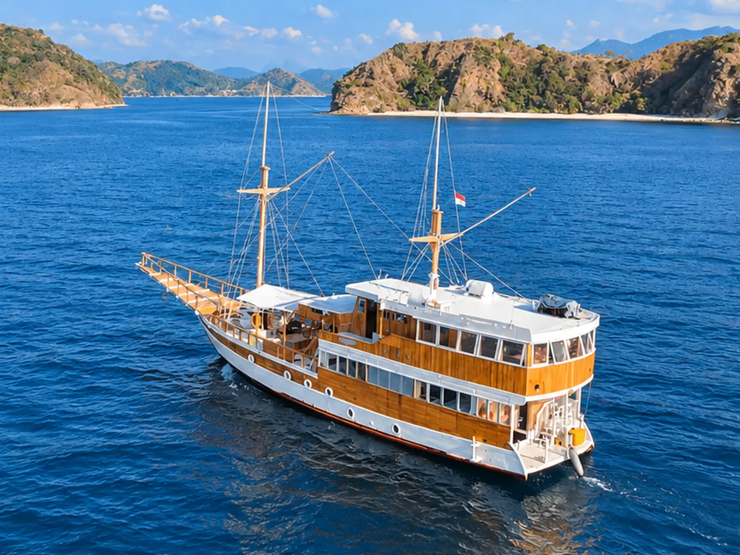 NK Jaya, a three-deck wooden phinisi with a white hull in Komodo National Park waters