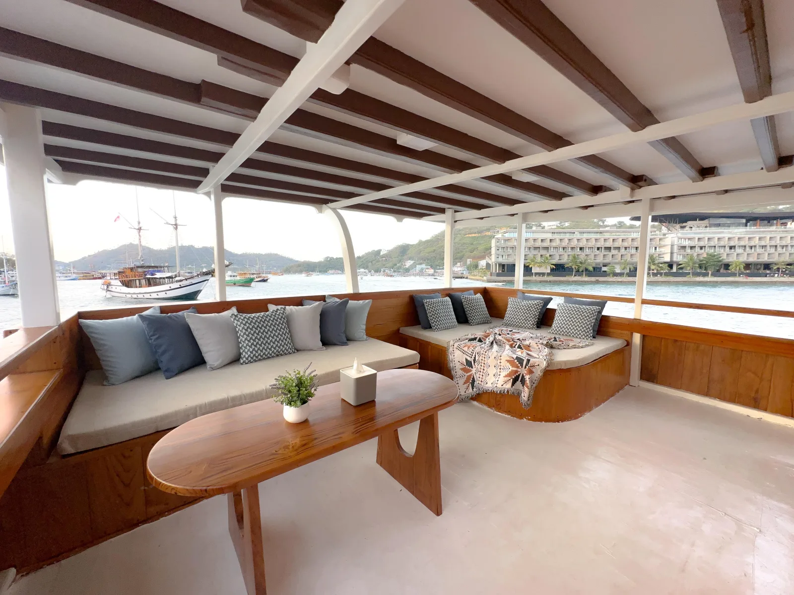 Ruang santai North Blue dengan sofa berbantal dan meja kayu menghadap laut