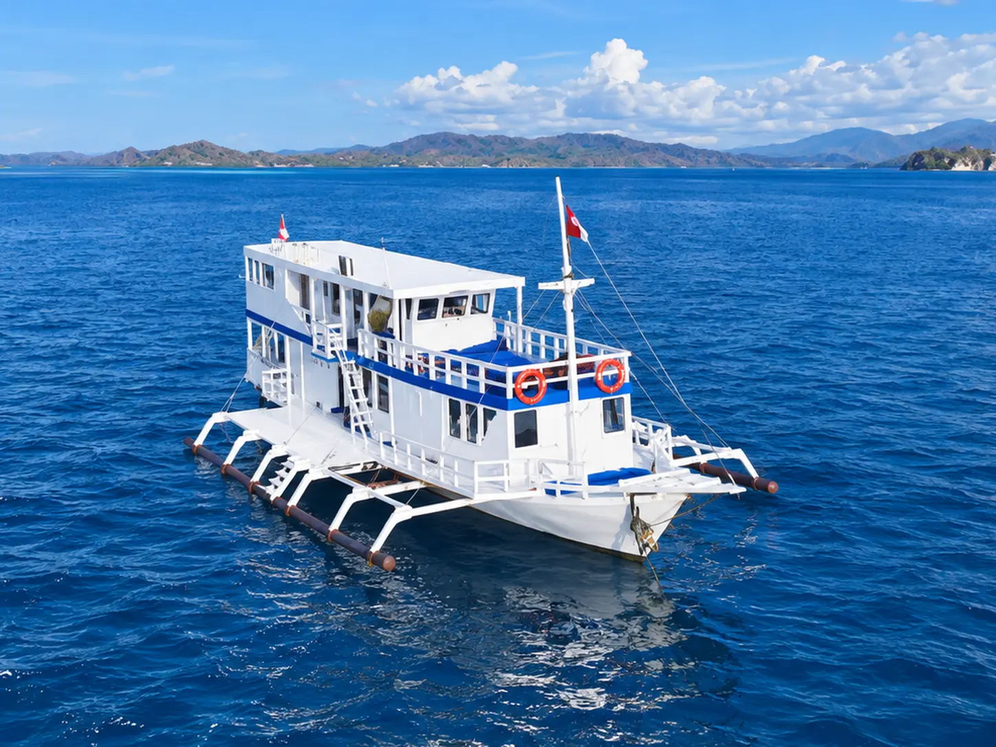 Osiana Alo, a multi-deck white boat with outriggers in Komodo National Park waters