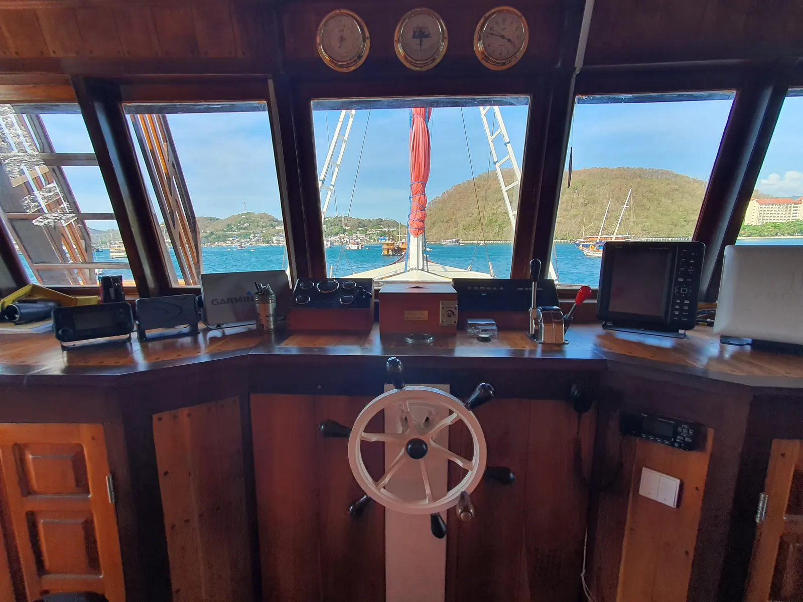 Ruang kemudi kayu Sea Familia II dengan roda kemudi dan panel navigasi
