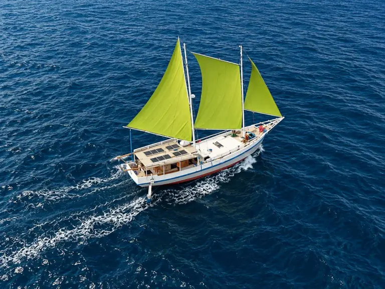 Kapal layar Sabbar Cruise dari udara, tiga layar hijau limau terkembang di laut biru