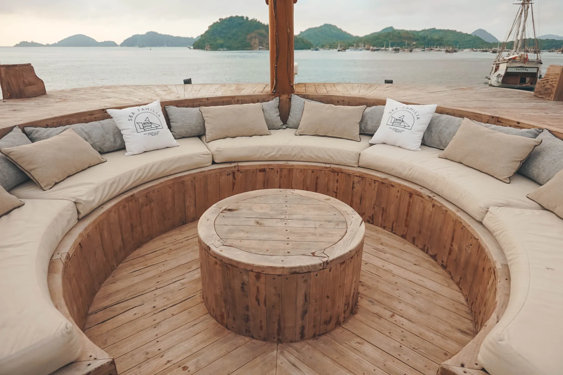 Sofa bundar cekung dengan meja kayu di dek depan Sea Familia I