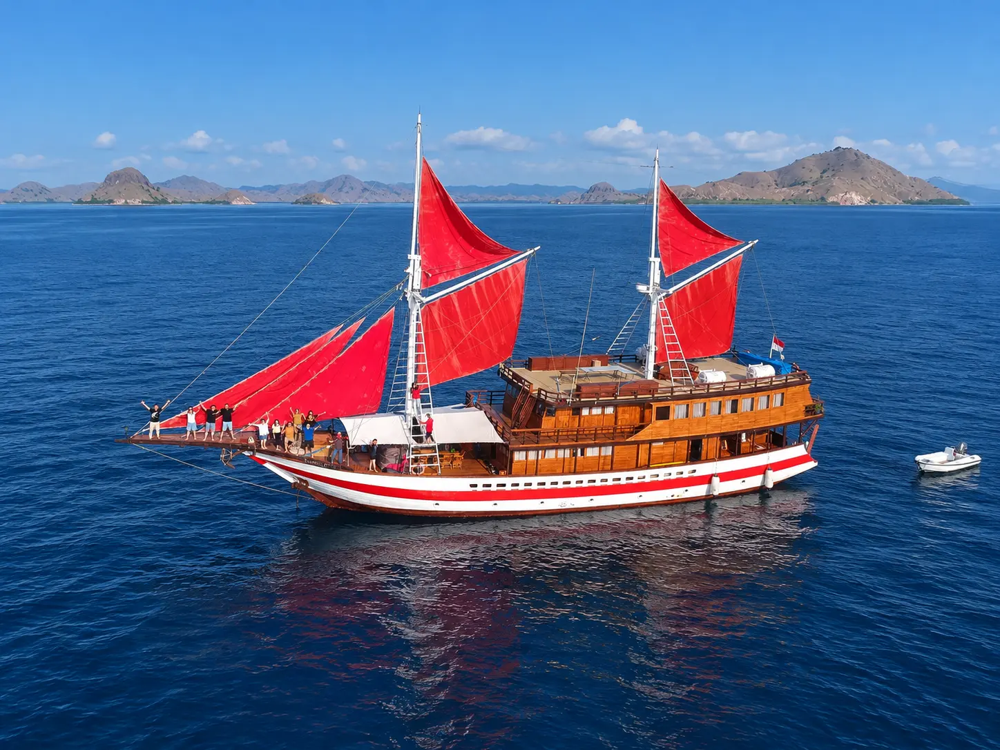 Sea Familia II, a wooden phinisi with red sails in Komodo National Park waters