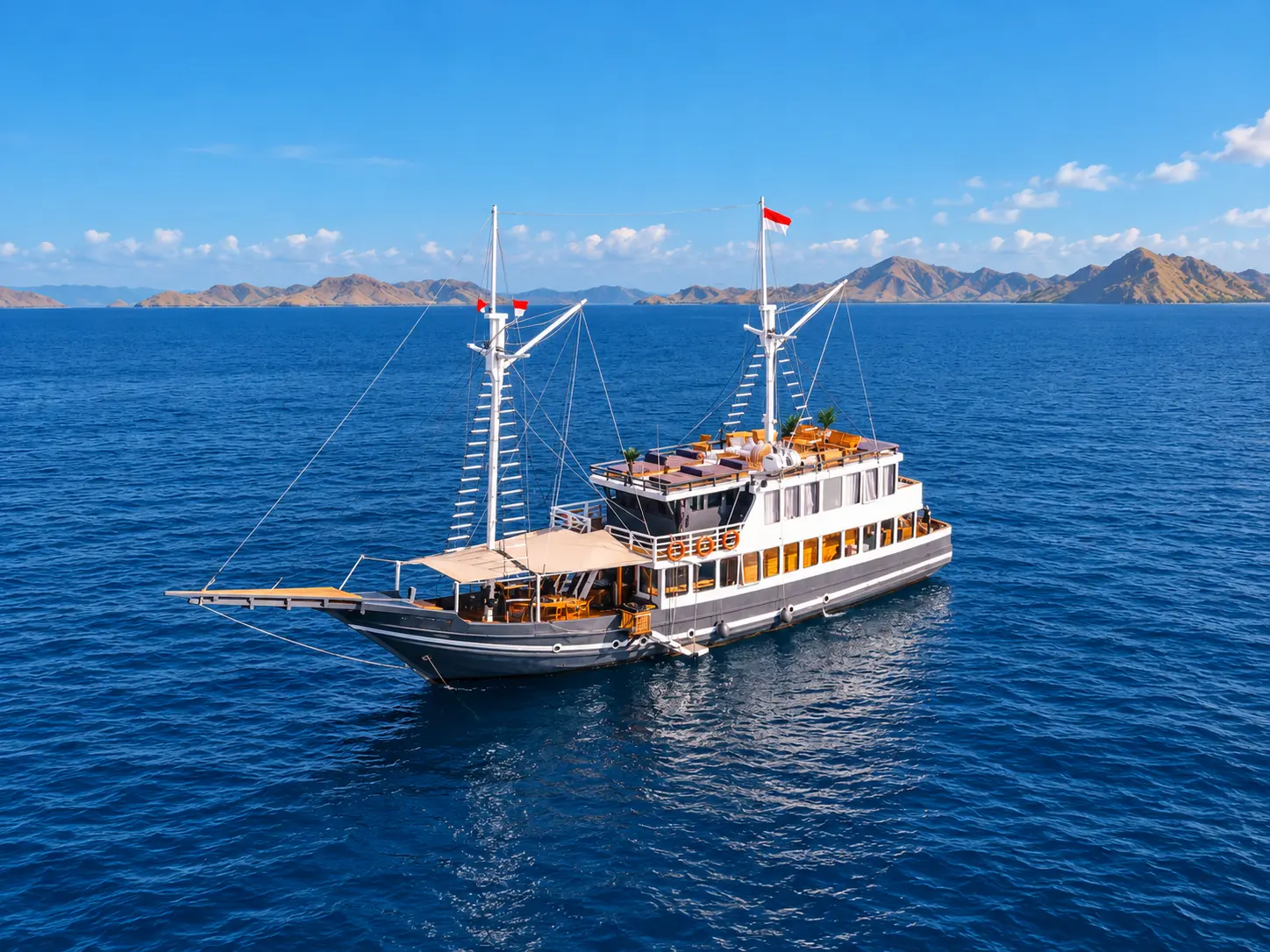 Semesta Voyages, a multi-deck phinisi with a grey hull in Komodo National Park waters