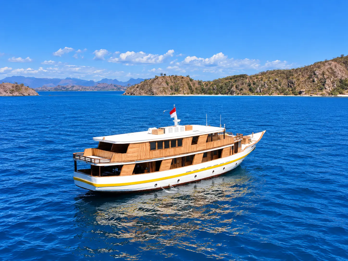 Vhalé Liveaboard, a white-hulled wooden boat with a yellow stripe in Komodo National Park waters