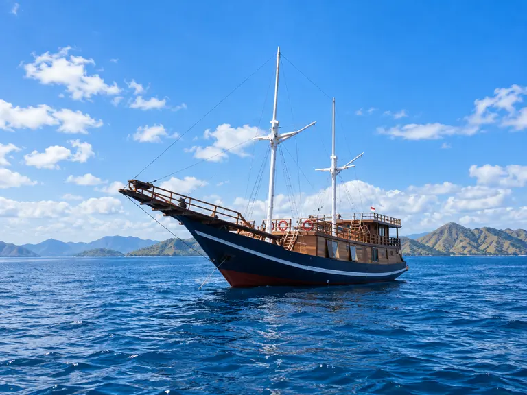 Walenreng Liveaboard, a wooden phinisi with a navy blue hull in Komodo National Park waters
